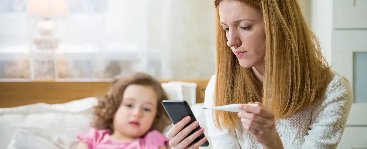 A woman holding a cell phone with a baby in front of her.
